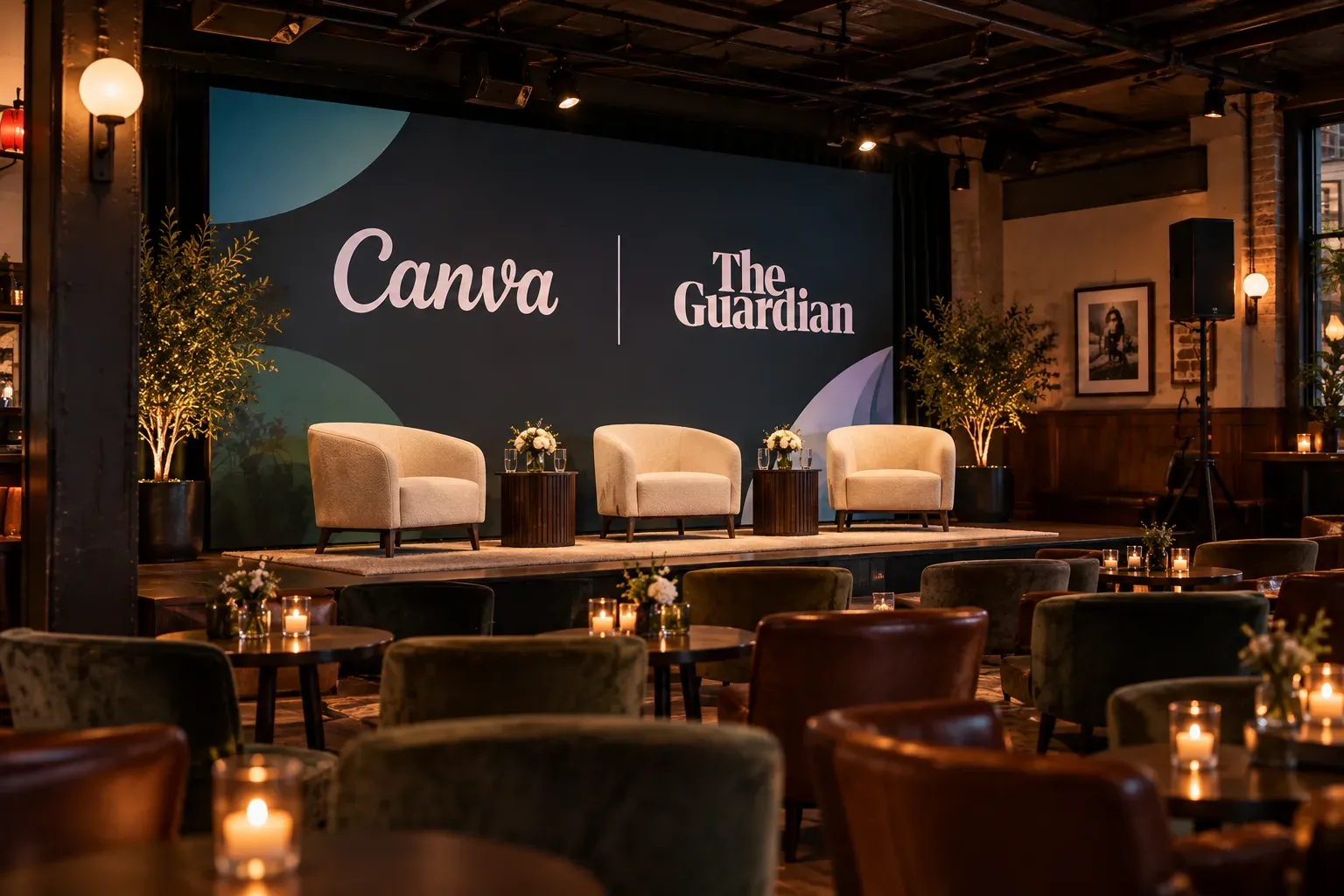 Event stage with Canva and The Guardian logos, three cream chairs, and ambient candlelit seating in upscale venue.